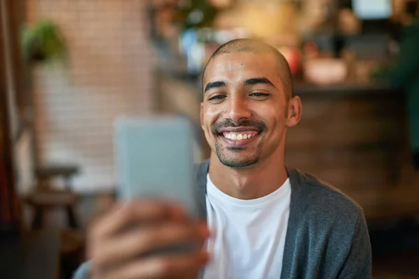 Estarei à tua espera no café. Tiro recortado de um jovem a enviar mensagens no telemóvel num café. — Fotografia de Stock