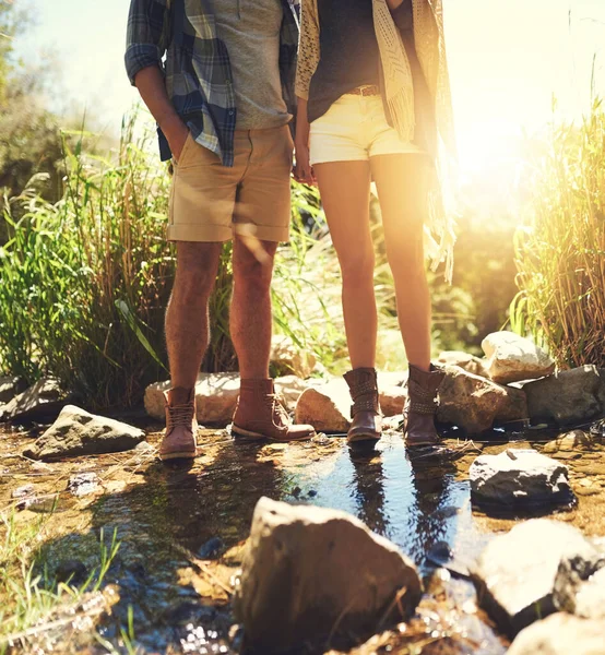 De är ett jordpar. Beskuren bild av ett par som står tillsammans i en stenig ström. — Stockfoto