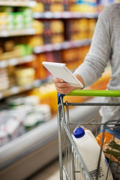 Asegurándose de que obtenga todo lo necesario. Primer plano de una mujer revisando su lista de compras en una tienda de comestibles. —  Fotos de Stock