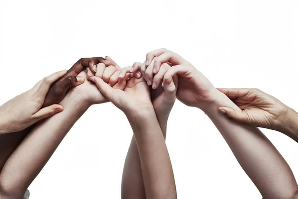 Eenheid omarmen door diversiteit. Opname van een groep handen die elkaar vasthouden tegen een witte achtergrond. — Stockfoto