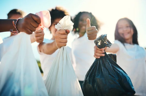 Meldepflicht für Aufräumarbeiten. Aufnahme einer Gruppe von Teenagern, die Müll von einem Feld aufheben und Daumen hoch im Sommerlager zeigen. — Stockfoto
