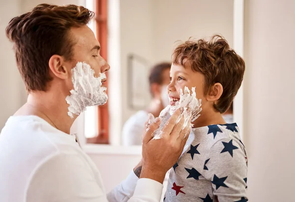 Now is a good time for his first shaving lesson. Shot of a man teaching his young son how to shave at home. — Stock Photo, Image