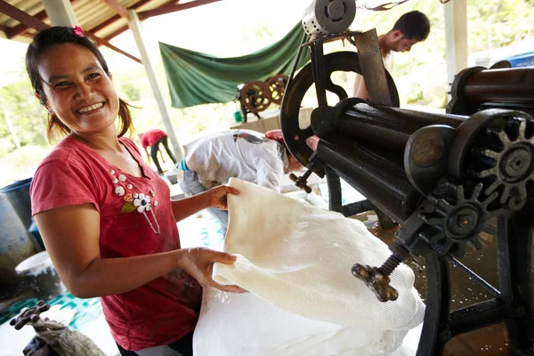 La soddisfazione del lavoro. Una donna tailandese sorride mentre stende fogli di gomma. — Foto Stock
