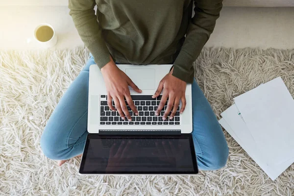 Працює у своєму блозі. Знімок невпізнаваної молодої жінки, яка використовує свій ноутбук, сидячи на підлозі вітальні . — стокове фото