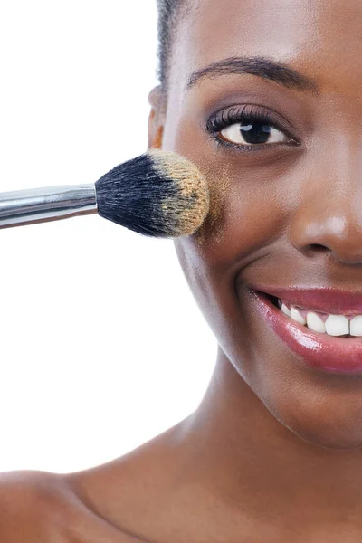 Fundación para la gama de pieles más oscuras. Estudio de una joven modelo africana aplicando una base con un cepillo aislado en blanco. —  Fotos de Stock