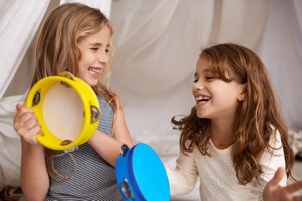 Musica e gioia. Girato di due bambine carine che giocano con i tamburelli a casa. — Foto Stock