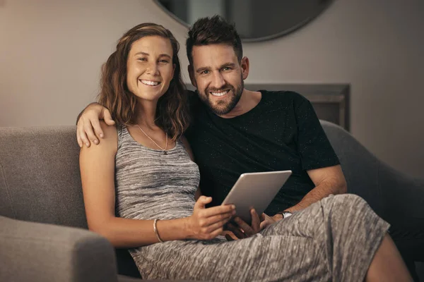 Llevar nuestro tiempo de calidad al sofá. Retrato de una pareja joven usando una tableta digital mientras se relajan en el sofá en casa. — Foto de Stock