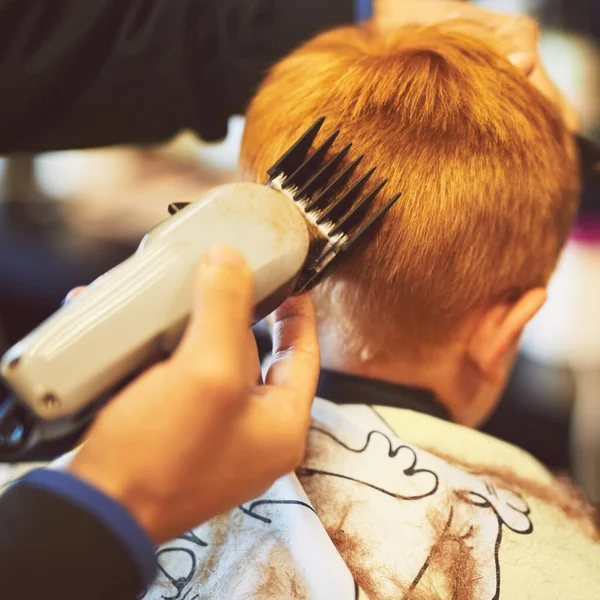 C'est l'heure d'un nouveau look. Gros plan d'un jeune garçon se faisant couper les cheveux dans un salon de coiffure. — Photo