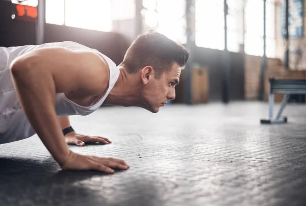 You were built to be the best. Shot of a young man doing pushups in a gym. — Stock Photo, Image