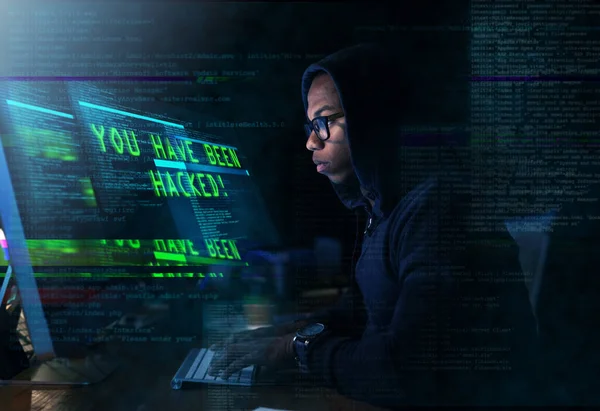 Cyberoorlog. Gehakte foto van een jongeman die een beveiligd computernetwerk hackt. — Stockfoto