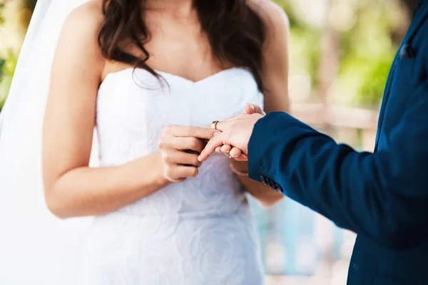 With this thing I vow to always love you. Cropped shot of an unrecognizable bride slipping a ring on to her grooms finger while standing outdoors on their wedding day. — Stock Photo, Image
