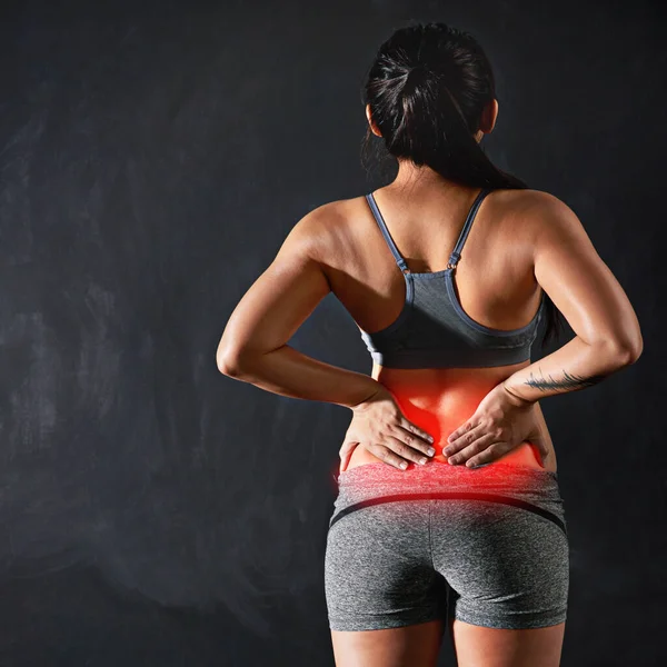 Esta vez se excedió. Vista trasera de una deportista no identificable sosteniendo su espalda después de lesionarla. —  Fotos de Stock