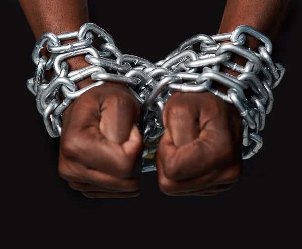 Otrok systému. Vystřižený snímek muže ruce svázané řetězy na černém pozadí. — Stock fotografie