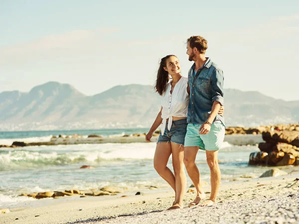 Wir teilen eine tiefe Liebe zum Strand. Aufnahme eines jungen Ehepaares beim Spazierengehen am Strand. — Stockfoto