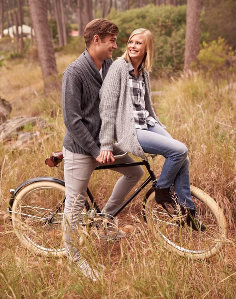 Necesito que me lleves. Una joven pareja disfrutando de un paseo en bicicleta al aire libre juntos. — Foto de Stock