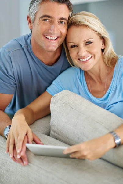 Were a modern couple. Portrait of a smiling couple sitting at home using a digital tablet. — Stock Photo, Image