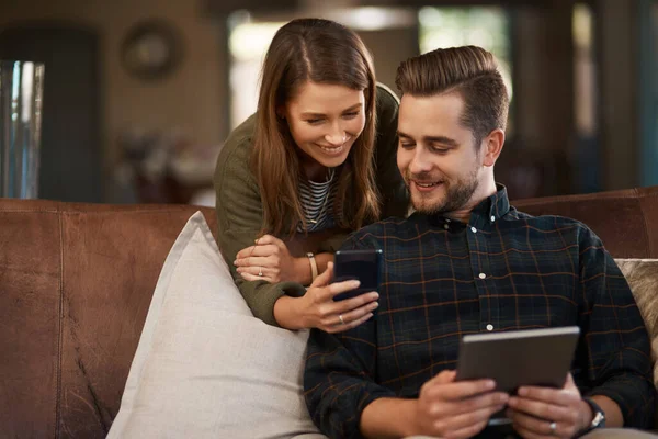 Ottenere questa applicazione sul tablet. Foto ritagliata di una giovane coppia che usa un cellulare e un tablet digitale a casa. — Foto Stock