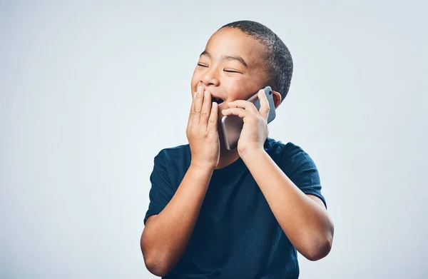 Una llamada de la abuela siempre le da la risa. Captura de estudio de un lindo niño que se ve sorprendido mientras usa un teléfono inteligente contra un fondo gris. — Foto de Stock