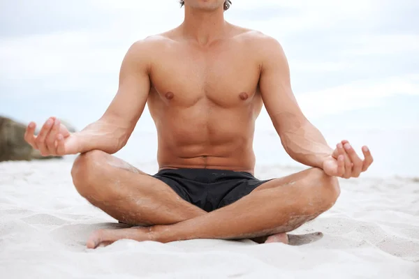 Doğa onu cezalı tutuyor. Genç yakışıklı adam sahilde oturmuş meditasyon yapıyor.. — Stok fotoğraf