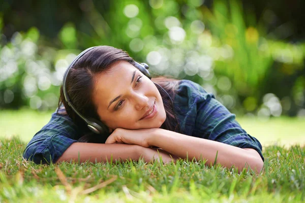 Soñando con las cosas por venir. Foto de una joven atractiva tumbada en la hierba y escuchando música. — Foto de Stock