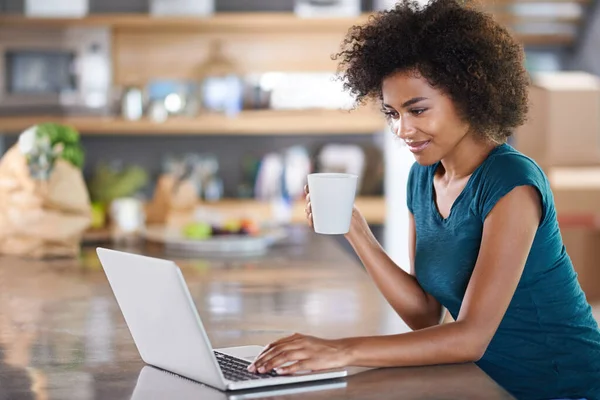 Tomando café con un amigo. Mujer joven usando un ordenador portátil mientras bebe de una taza. — Foto de Stock
