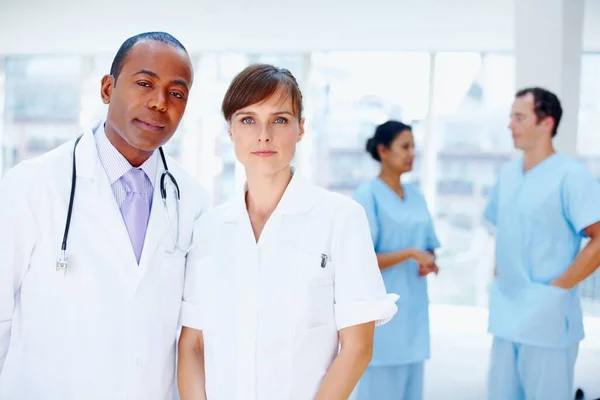 Doktoři vypadají vážně. Lékaři stojí spolu se sestrami v pozadí. — Stock fotografie
