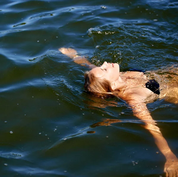 Zadziwiająco orzeźwiające. Strzał atrakcyjnej młodej kobiety unoszącej się na plecach w jeziorze. — Zdjęcie stockowe