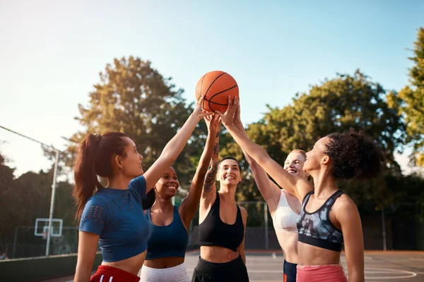 Nu gör vi det här, flickor. Beskuren skott av en diversifierad grupp av idrottskvinnor som håller en basket tillsammans innan du spelar ett spel under dagen. — Stockfoto