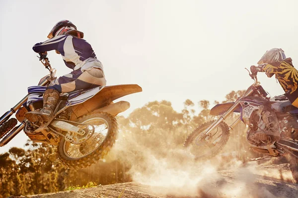 Пора разорвать этот трек. Снимок двух гонщиков на грязных мотоциклах, идущих лицом к лицу на трассе. — стоковое фото