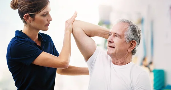 Laat het me weten als je je ongemakkelijk voelt. Shot van een aantrekkelijke jonge vrouwelijke fysiotherapeut werken met een senior mannelijke patiënt. — Stockfoto