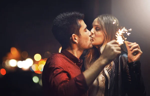Когда мы целуемся, искры летят. Снято счастливой молодой парой, празднующей со сверкающими на улице ночью. — стоковое фото