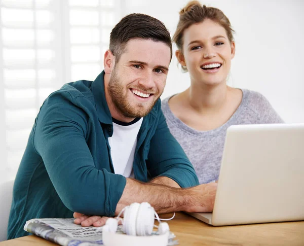 Somos um casal ligado. Retrato de um jovem casal sorrindo usando um laptop enquanto relaxam em casa juntos. — Fotografia de Stock