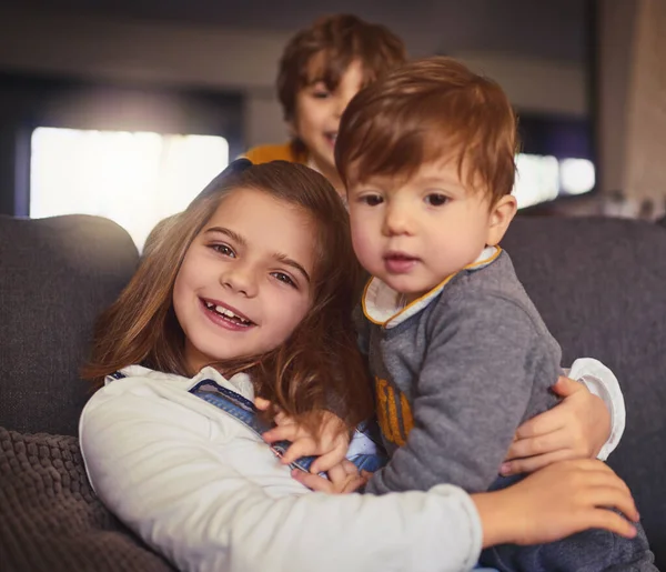 Det är den sötaste. Beskärda porträtt av en bedårande liten flicka och hennes två bröder i deras vardagsrum hemma. — Stockfoto
