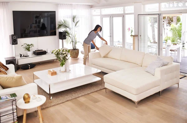 Tidying before her guests arrive. Shot of a young woman tidying her house.