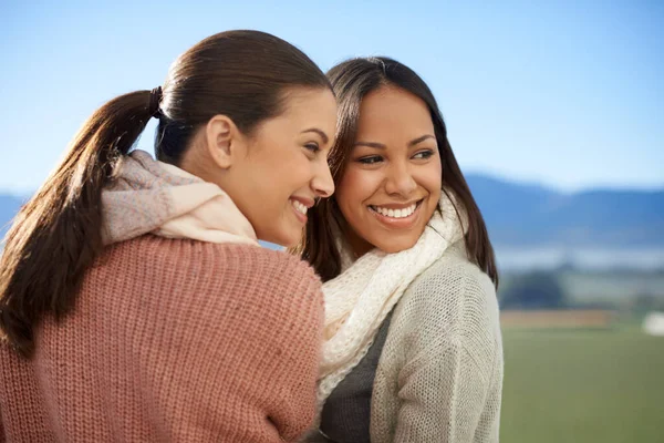 Друзья - через хорошие времена и плохие. Две молодые женщины стоят снаружи и счастливо улыбаются.. — стоковое фото