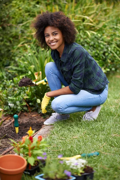 Sujar-lhe as mãos. Retrato de uma jovem mulher feliz plantando flores no jardim. — Fotografia de Stock