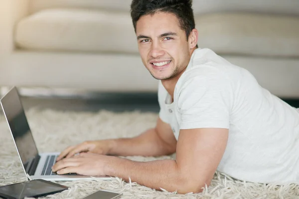 Hoe meer draadloos, hoe stressloos. Portret van een ontspannen jongeman met behulp van een laptop op de vloer thuis. — Stockfoto