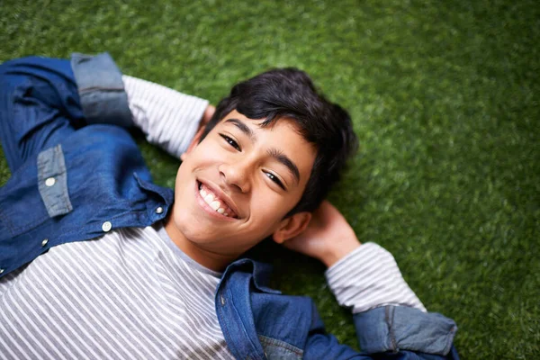 É incrível ser uma criança. Um menino relaxando no gramado. — Fotografia de Stock