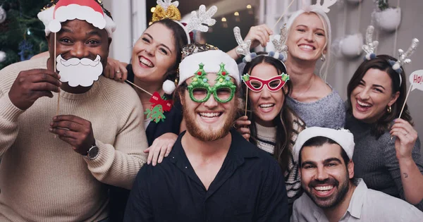 Vegyétek fel a kalapotokat, itt a karácsony. Egy fiatal baráti társaság portréja, akik vicces kalapot és szemüveget viselnek egy karácsonyi partin.. — Stock Fotó