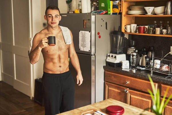 Café é a melhor coisa para se ter de manhã. Tiro cortado de um belo jovem sem camisa bebendo uma xícara de café na cozinha em casa. — Fotografia de Stock