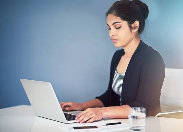 Jobbar flitigt. Beskuren bild av en attraktiv ung affärskvinna som arbetar på en bärbar dator på sitt kontor. — Stockfoto