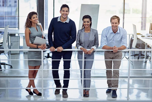 We doen het met een glimlach. Portret van een groep lachende collega 's die samenwerken in een kantoor. — Stockfoto