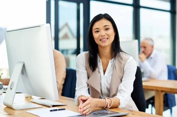 Réussir avec un sourire. Portrait recadré d'une jeune femme d'affaires travaillant dans son bureau avec des collègues en arrière-plan. — Photo