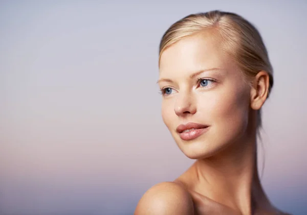 Ik denk aan nieuwe schoonheidstechnieken. Een mooi jong model dat over haar schouder kijkt tegen een zachte paarse achtergrond. — Stockfoto