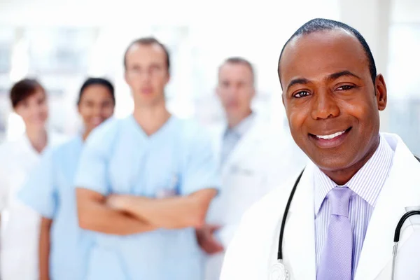 Confident doctor with medical team in background. Focus on doctor with colleagues in background. — Stock Photo, Image