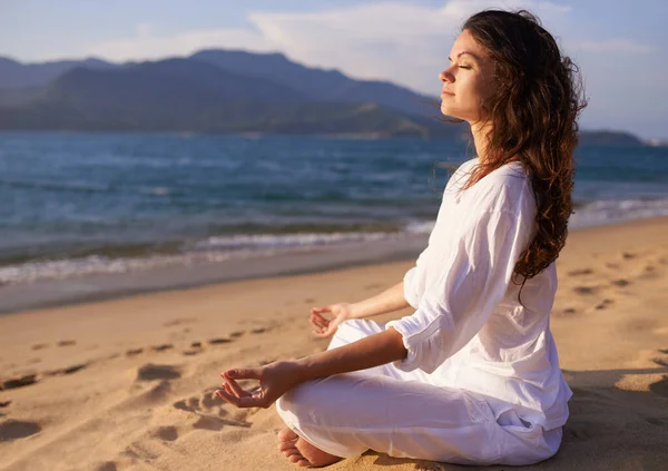 El resort perfecto para encontrar la paz interior. Foto de una joven haciendo yoga en la playa. — Foto de Stock