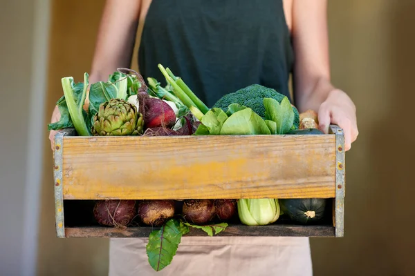 Het groene leven leiden. Een jonge vrouw met een krat groenten buiten. — Stockfoto