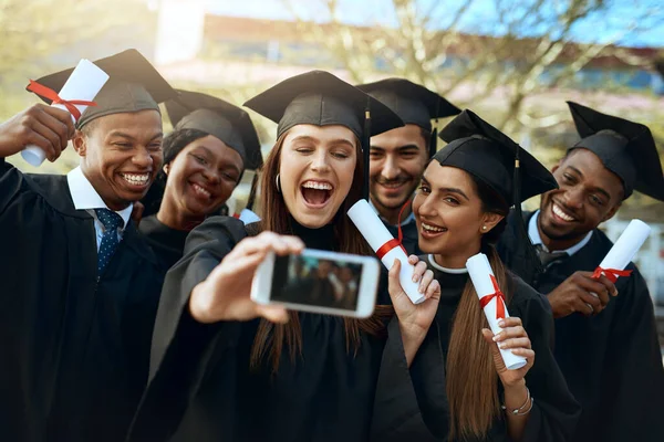 Mundo de trabalho, aqui vamos nós. Tiro de um grupo de estudantes que tomam selfies com um telefone celular no dia da graduação. — Fotografia de Stock