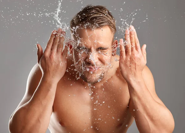 I dont have time for oil and grime. Studio shot of a handsome young man washing his face against a grey background. — Stock Photo, Image