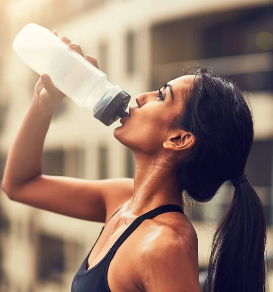 Trinkwasser ist unverzichtbar für Ihre Gesundheit. Schnappschuss einer sportlichen jungen Frau, die nach ihrem Lauf Wasser trinkt. — Stockfoto